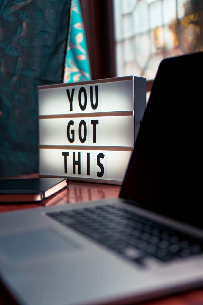 A laptop sits open with a lighbox sat beside it spelling "YOU GOT THIS."